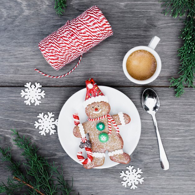 Bonhomme de neige en biscuit sur une assiette près d&#39;une tasse de boisson, de flocons de neige et de fils