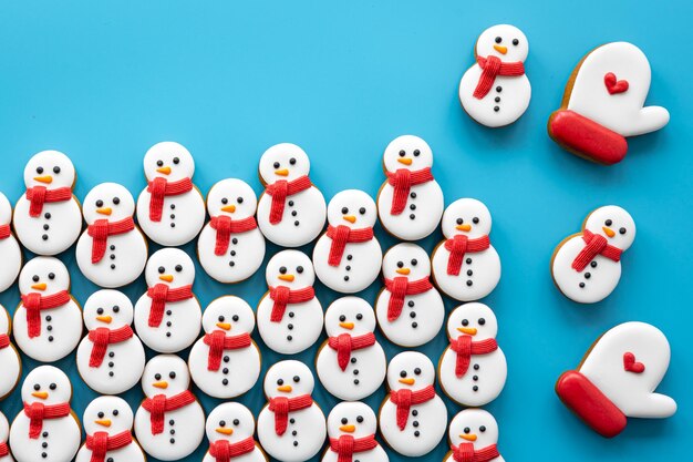 Bonhommes de neige en pain d'épice recouverts de glaçage sur fond bleu à plat