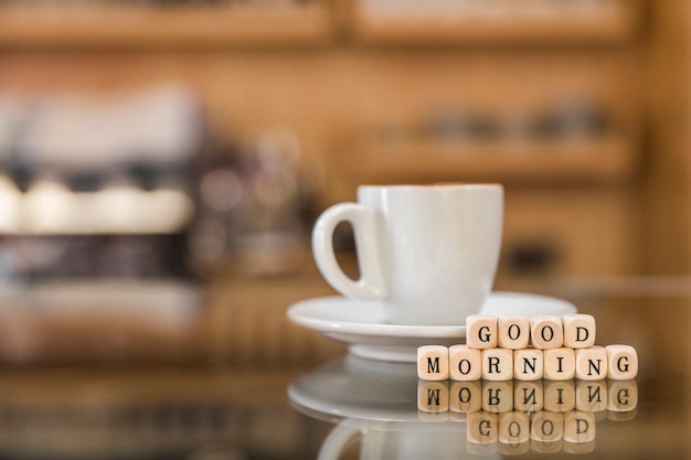 Photo gratuite bonjour blocs de bois avec une tasse de café sur le comptoir de verre
