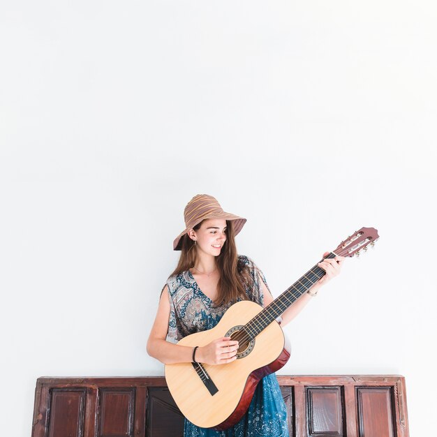 Bonne adolescente jouant de la guitare devant le mur