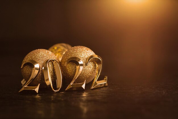 Bonne année 2022 nombres d'or fond en bois noir boules d'or et décorations de noël