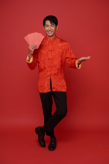 Photo gratuite bonne année chinoise 2024 homme asiatique portant des vêtements traditionnels rouges tenant un angpao