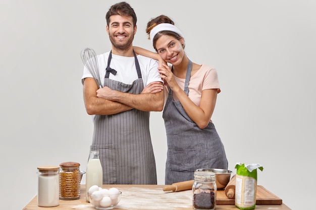 Une bonne équipe amicale de chefs professionnels pose ensemble à la cuisine, satisfaits du bon travail, prépare un repas, se tient debout l'un à côté de l'autre, utilise différents ingrédients pour cuire des confiseries pour le petit-déjeuner à la maison