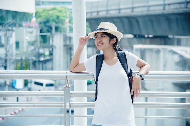 Bonne étudiante asiatique souriante avec sac à dos au fond de la ville