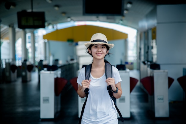 Bonne étudiante asiatique souriante avec sac à dos au fond de la ville