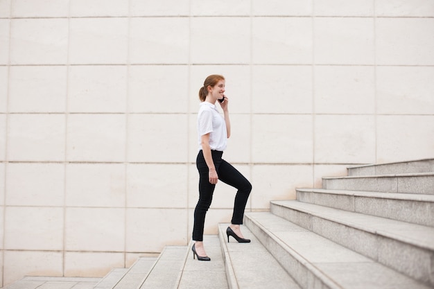 Photo gratuite bonne femme d'affaires qui monte à l'étage et qui appelle