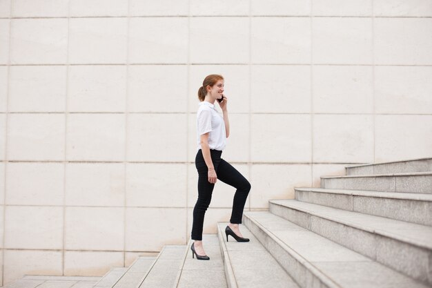 Bonne femme d&#39;affaires qui monte à l&#39;étage et qui appelle