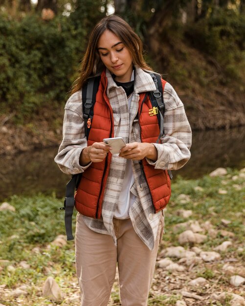 Bonne fille de camping dans la forêt à l'aide de téléphone mobile