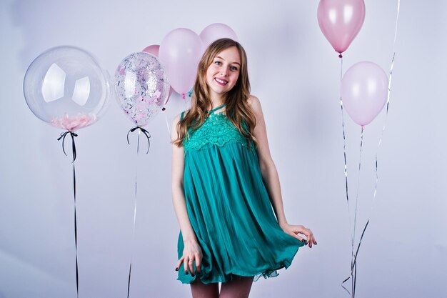 Bonne fille en robe turquoise verte avec des ballons colorés isolés sur blanc Célébrer le thème de l'anniversaire