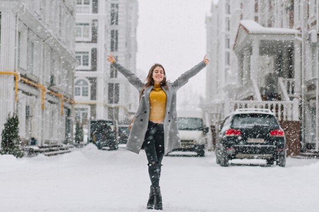 Bonne heure d'hiver de neige dans la grande ville de jolie fille appréciant les chutes de neige sur la rue. De vraies émotions positives, se tenant la main dessus,