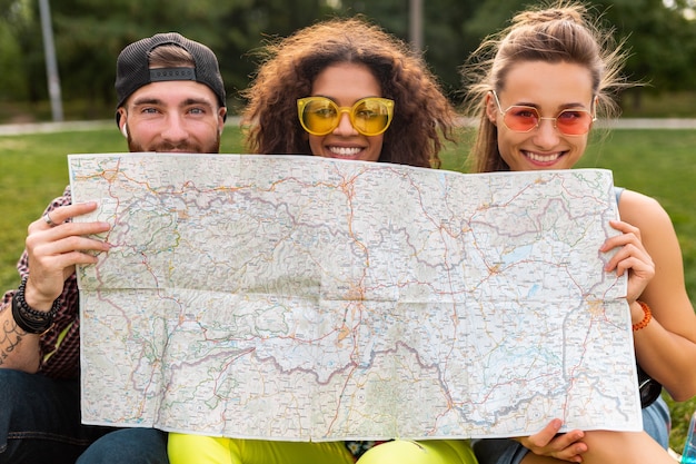 Bonne jeune compagnie drôle d'amis touristes se cachant derrière la carte dans des lunettes de soleil, homme et femme s'amusant ensemble, voyageant