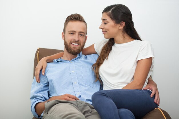 Bonne jeune couple assis sur l&#39;entraîneur à la maison