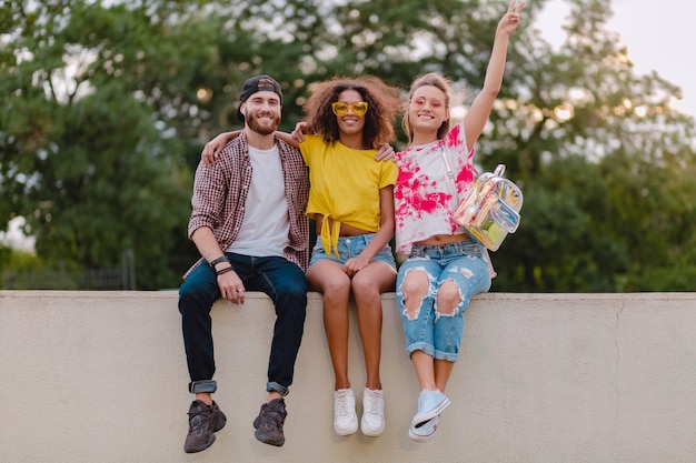 Photo gratuite bonne jeune entreprise d'amis souriants assis dans le parc, l'homme et la femme s'amusant ensemble