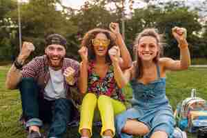 Photo gratuite bonne jeune entreprise d'amis souriants assis parc sur l'herbe, l'homme et la femme s'amusant ensemble