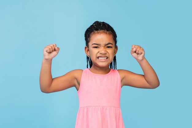 Bonne petite fille brune aux cheveux longs isolée sur fond de studio bleu a l'air heureux joyeux sincère Copyspace concept d'émotions de l'éducation de l'enfance