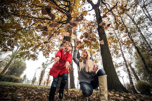 Bonne petite fille jetant des feuilles sèches