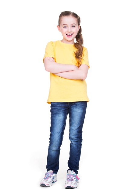 Bonne petite fille joyeuse avec les mains croisées regardant la caméra en pleine longueur debout sur fond blanc.