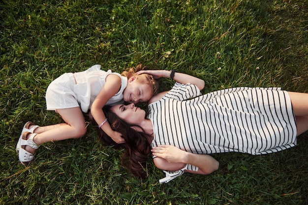 Bonne petite fille et sa mère s'amusant à l'extérieur sur l'herbe verte en journée d'été ensoleillée.