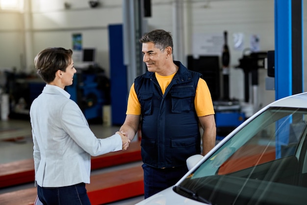 Bonne poignée de main de réparateur automobile avec une cliente dans un atelier