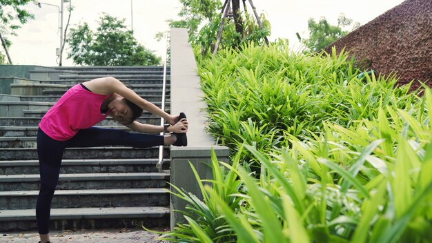 En bonne santé belle jeune athlète asiatique femmes en vêtements de sport jambes réchauffement et étirement