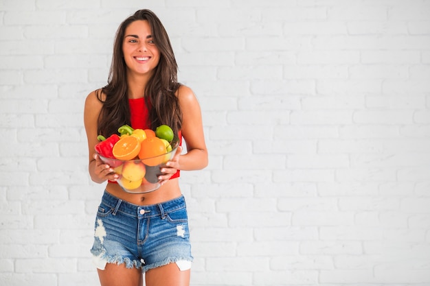 En bonne santé jeune femme tenant des légumes frais et des fruits dans un bol
