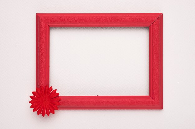 Une bordure rouge en bois vide avec fleur sur mur blanc