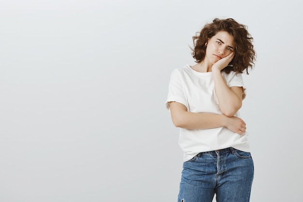 Bored jolie fille s'appuyant sur la paume et regardant avec indifférence et ennui