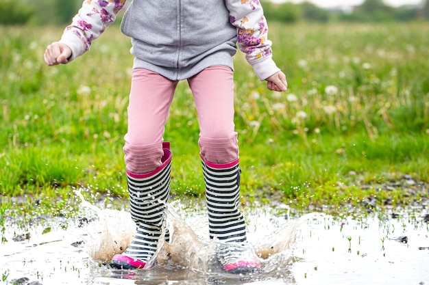 Bottes en caoutchouc dans une flaque d'eau en train de sauter avec des éclaboussures d'eau