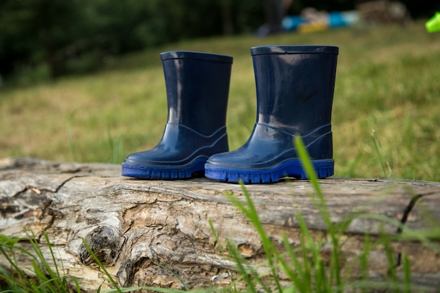 bottes en caoutchouc pour enfants se tiennent sur la poutre, le concept de camping et de loisirs