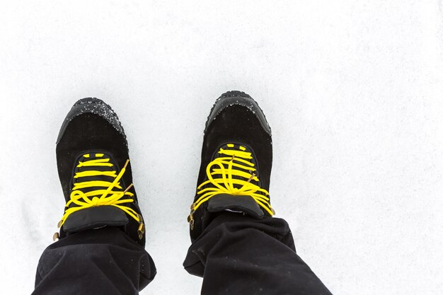 Bottes noires avec des lacets jaunes sur la neige