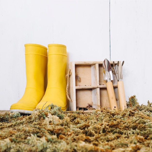 Photo gratuite bottes de pluie et outils sur mousse sèche