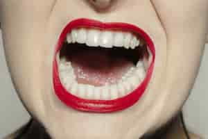 Photo gratuite bouche féminine close-up avec du maquillage des lèvres brillant rouge vif.