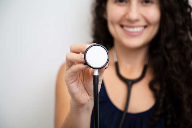 Bouchent femme souriante tenant un stéthoscope