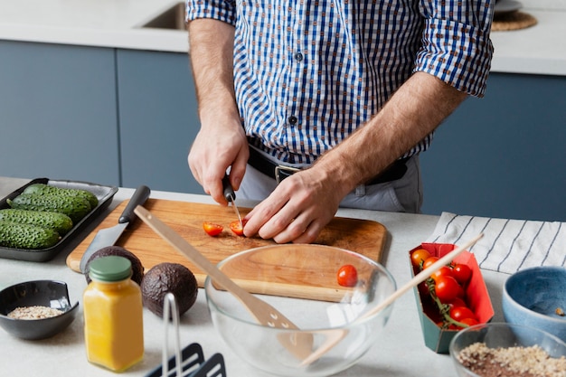 Bouchent les mains coupant la tomate