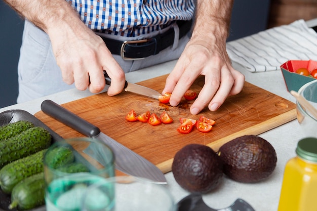 Bouchent les mains coupant des tomates