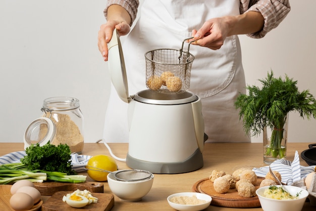 Bouchent les mains faisant frire les croquettes de nourriture