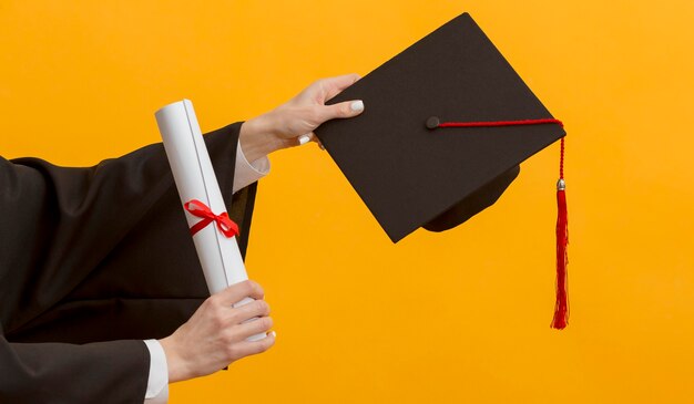 Bouchent les mains tenant un diplôme et une casquette