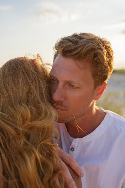 Bouchent le portrait de beau couple européen embrassant contre le coucher du soleil.