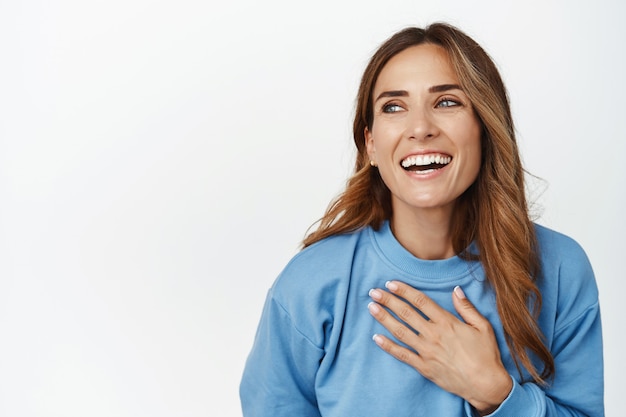 Bouchent le portrait de la belle femme brune riant, souriant et tenant la main sur la poitrine