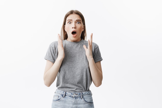 Bouchent le portrait de la belle fille mature aux cheveux noirs dans des vêtements décontractés, écartant les mains avec une expression surprise, voyant son petit enfant va prendre le couteau dans les mains.