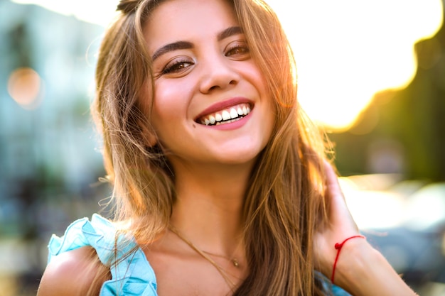 Bouchent le portrait ensoleillé de la belle femme magnifique avec un maquillage naturel et un grand sourire étonnant regardant la caméra, la lumière du soleil, une humeur positive.