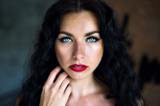 Bouchent le portrait d'une femme de beauté incroyable avec des poils bruns moelleux et gros bleu oui à la recherche droite, portant une montre blanche et un maquillage lumineux.