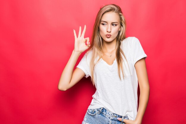 Bouchent le portrait de fille heureuse gesticulant signe ok isolé sur fond rouge