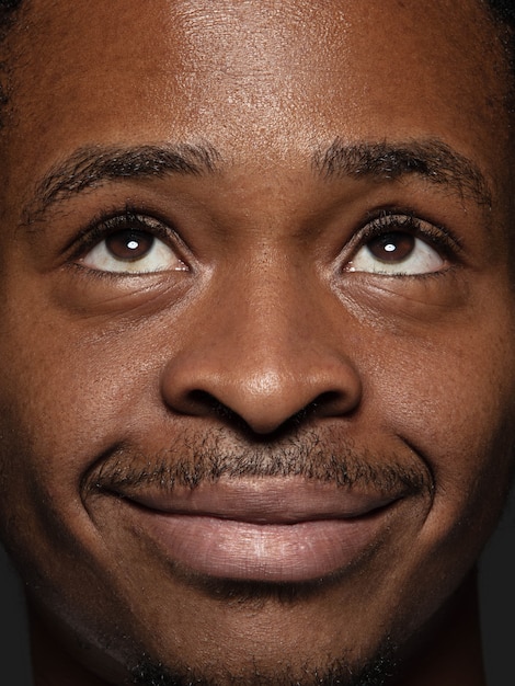 Photo gratuite bouchent le portrait d'un homme afro-américain jeune et émotionnel. photo très détaillée d'un modèle masculin avec une peau bien entretenue et une expression faciale brillante. concept d'émotions humaines. levant les yeux et sourire.