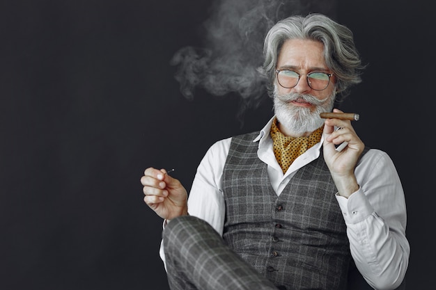 Photo gratuite bouchent le portrait d'un homme démodé souriant. grand-père avec un cigare et du whisky.