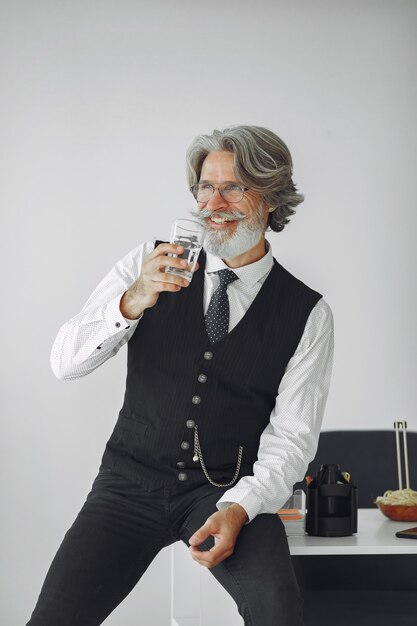 Bouchent le portrait d'un homme démodé souriant. Grand-père avec un verre d'eau.