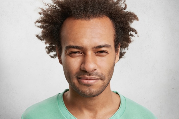 Photo gratuite bouchent le portrait d'un homme suspect à la peau sombre porte un pull vert, a une expression sérieuse