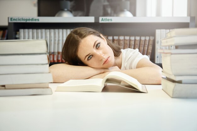 Bouchent le portrait de jeune étudiant à la bibliothèque se préparant pour les derniers examens, reposant sa tête sur les mains, l'air triste et fatigué