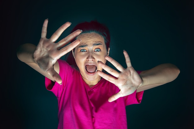 Photo gratuite bouchent le portrait d'une jeune femme folle effrayée et choquée isolée sur l'obscurité