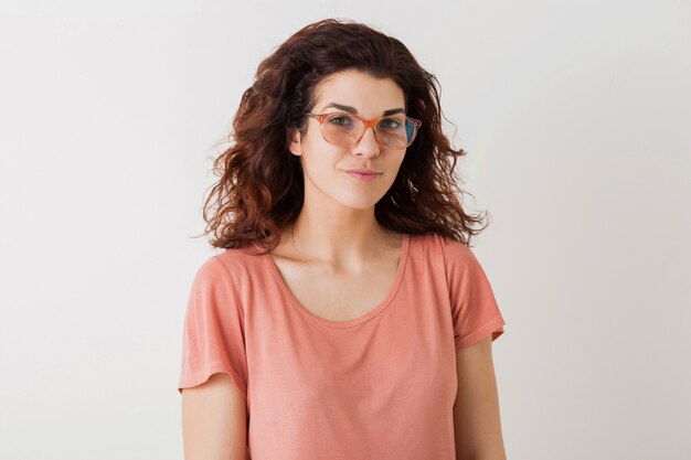 Bouchent le portrait de jeune femme jolie naturelle avec une coiffure frisée en chemise rose posant portant des lunettes isolées